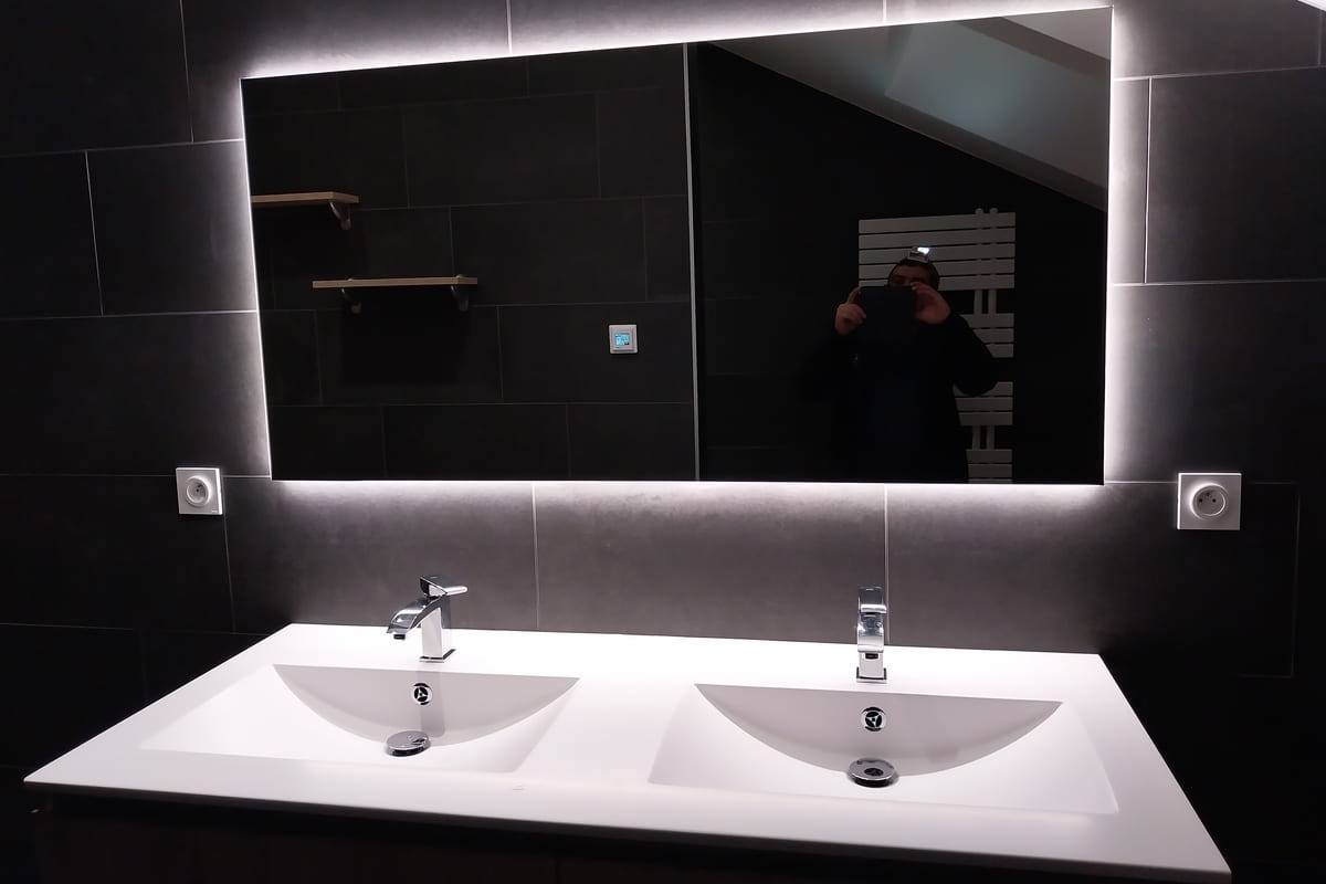 Salle de bains rénovée avec double vasque et miroir rétroéclairé